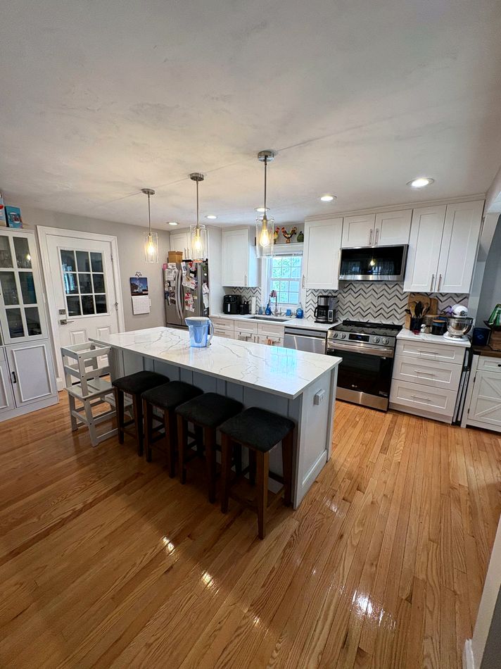 Bright, clean kitchen with white island and hardwood floors