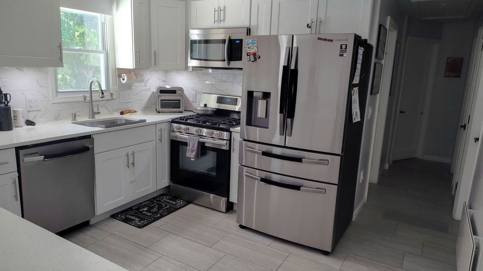 Bright white kitchen with stainless steel refrigerator