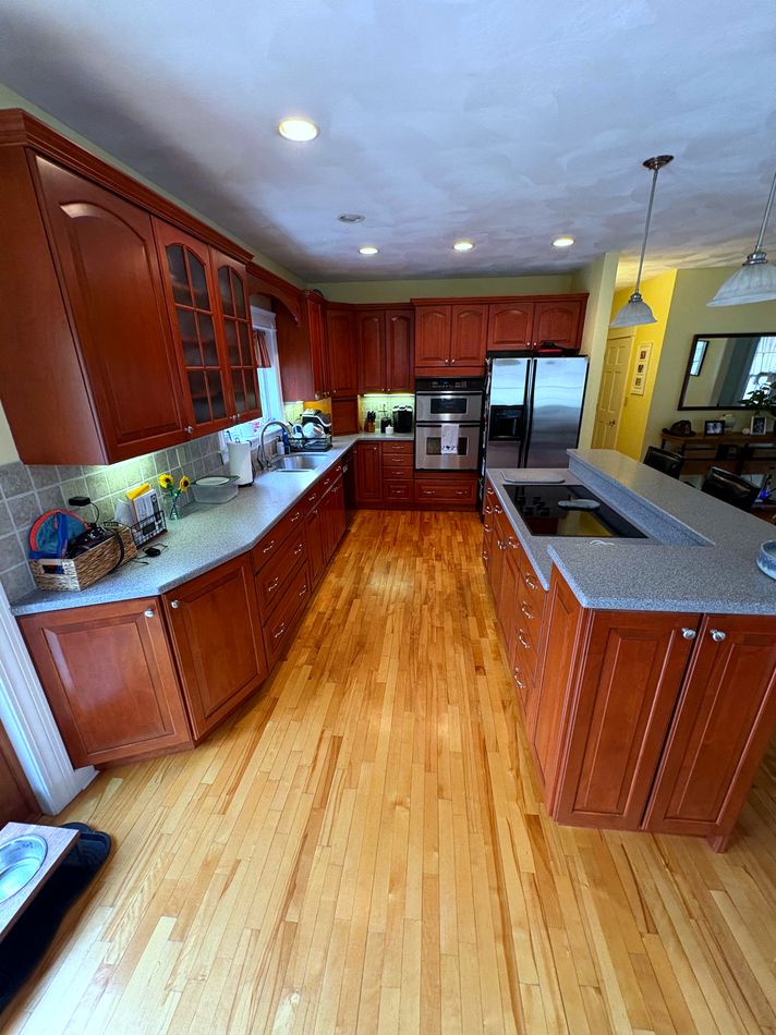 Clean kitchen with cherry wood cabinets and granite counters